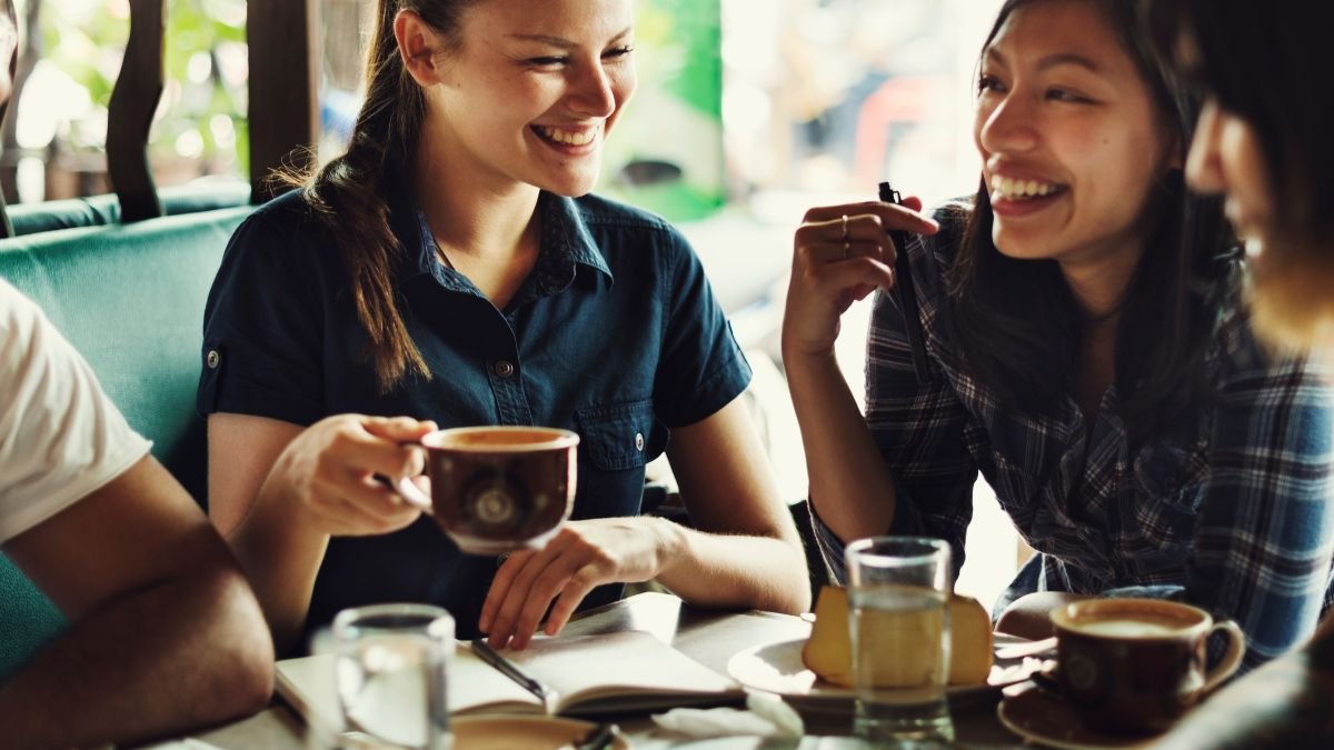 Két nő kávézik és nevetgél egy baráti találkozón egy kávézóban.