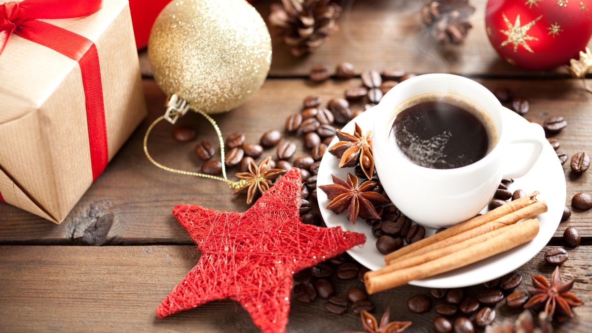Egy csésze fekete kávé, fahéjjal és csillagánizzsal díszítve, ajándékcsomag mellett.